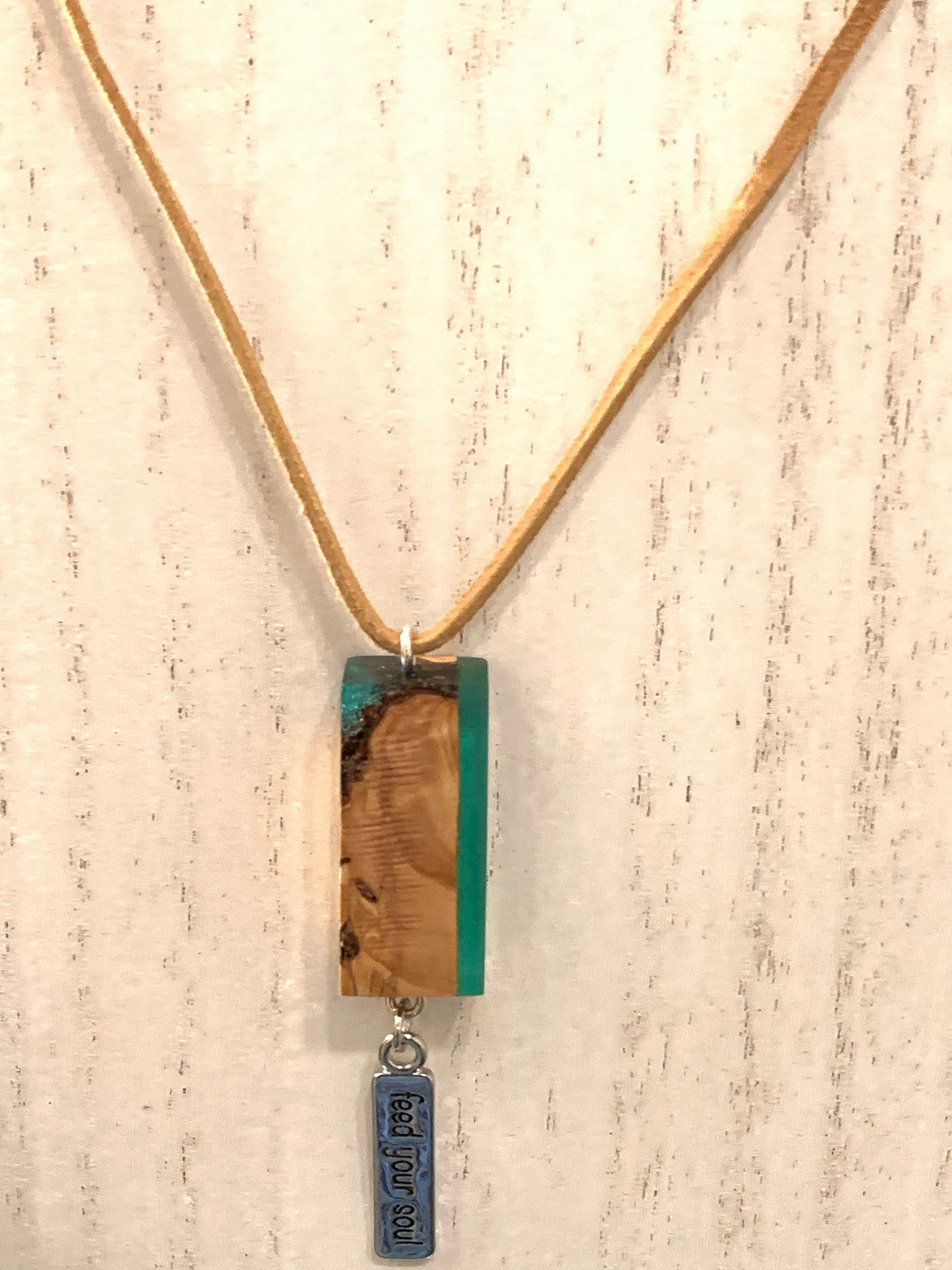 Green Resin and Wood pendant necklace with Feed Your Soul Charm hanging from beige suede necklace.