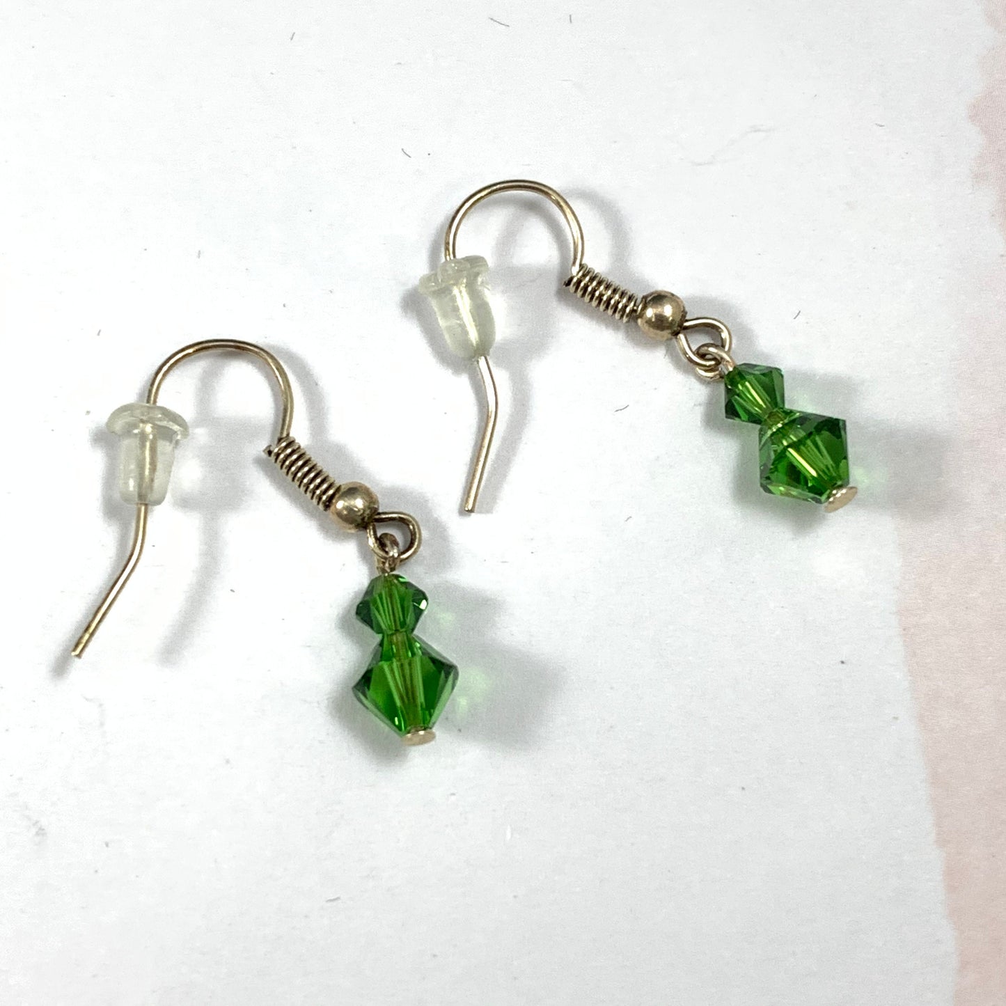 Silver earrings with 2 green crystal beads incorporated into the styling.